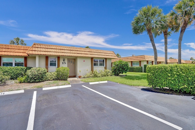 5730 Fernley Dr E Unit 15, West Palm Beach, FL 33415 - view of front facade featuring uncovered parking, stucco siding, a front yard, and a tile roof