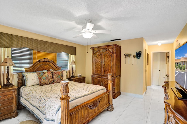 bedroom with a textured ceiling, a ceiling fan, visible vents, and multiple windows