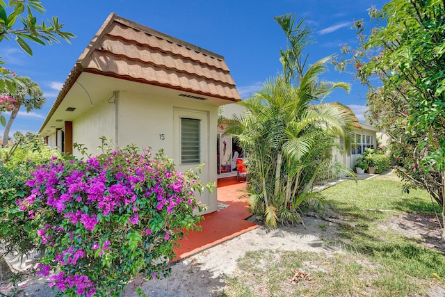 view of front of house featuring stucco siding, a tile roof, and a patio