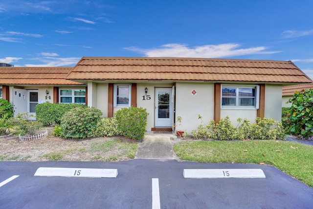single story home with a tiled roof, stucco siding, and uncovered parking