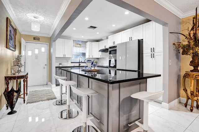 kitchen featuring marble finish floor, ornamental molding, visible vents, and a kitchen bar