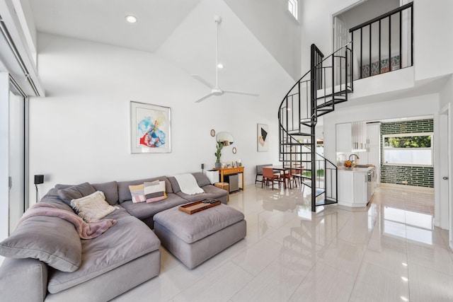 living room with light tile patterned floors, high vaulted ceiling, a ceiling fan, and stairs