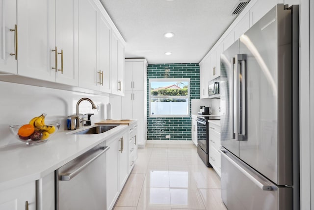 kitchen featuring a sink, appliances with stainless steel finishes, white cabinetry, and light countertops