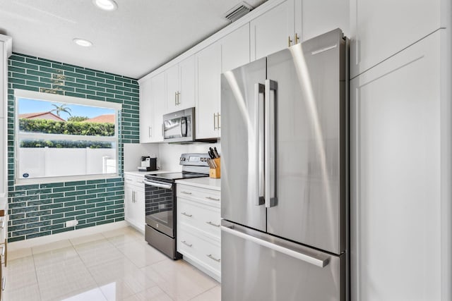 kitchen featuring recessed lighting, light countertops, white cabinets, light tile patterned floors, and stainless steel appliances