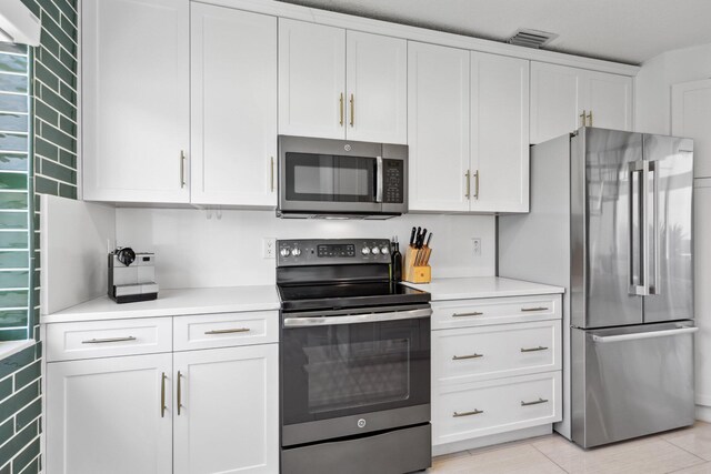 kitchen with light countertops, appliances with stainless steel finishes, white cabinets, and visible vents