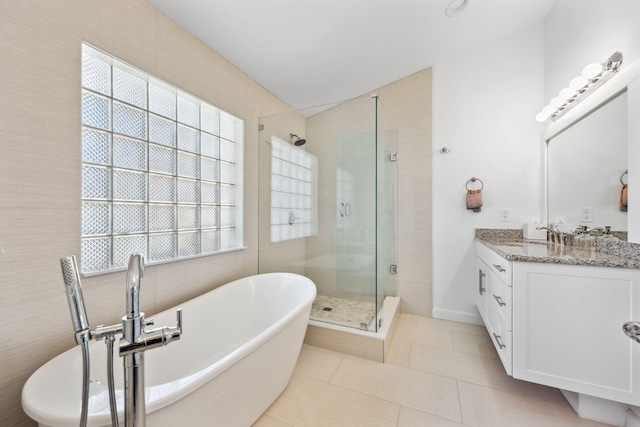 bathroom with vanity, tile patterned floors, a freestanding bath, a shower stall, and vaulted ceiling