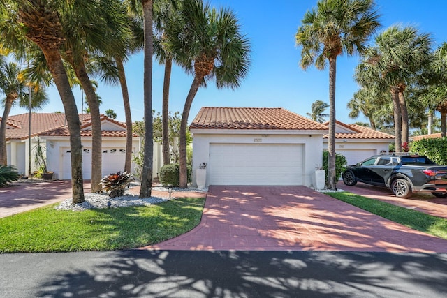 mediterranean / spanish-style house featuring decorative driveway, stucco siding, and a tiled roof