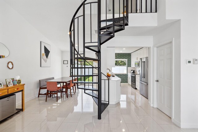 interior space featuring light tile patterned floors, baseboards, and stairs