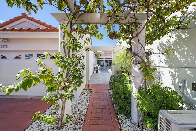 view of side of home featuring an attached garage, central AC, and stucco siding