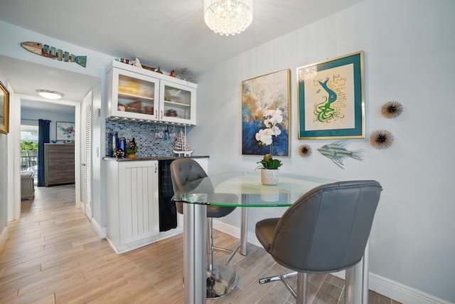 111 Doolen Ct Unit 208, North Palm Beach, FL 33408 - dining space featuring light wood-type flooring, a dry bar, a chandelier, and baseboards