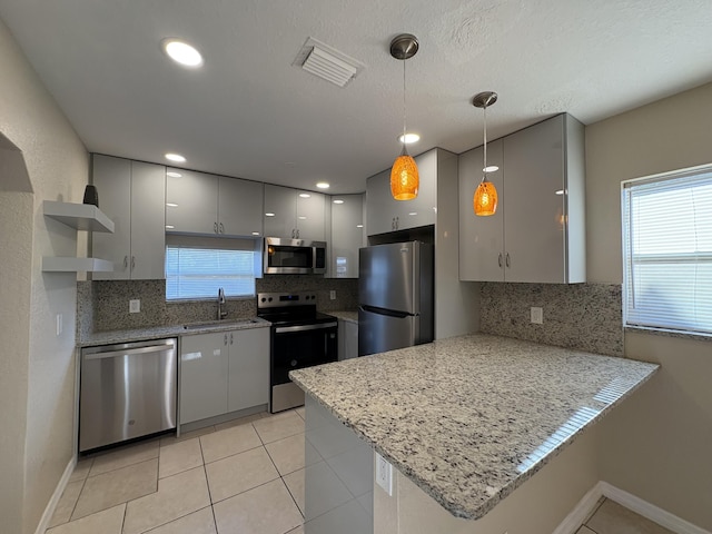 kitchen with a sink, a peninsula, stainless steel appliances, open shelves, and visible vents