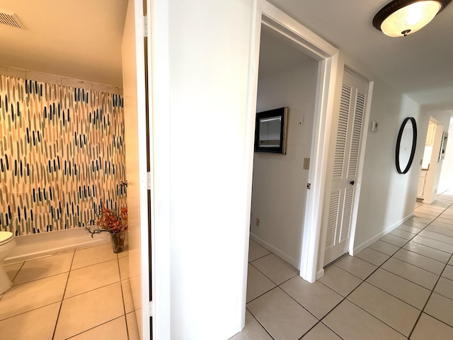 corridor featuring light tile patterned floors and baseboards