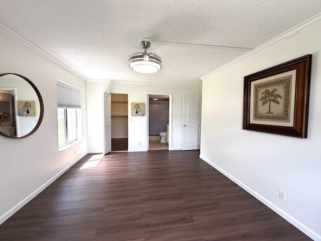 unfurnished dining area with crown molding, a textured ceiling, dark wood-style flooring, and baseboards