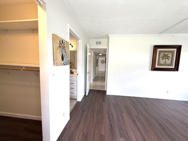 hallway with wood finished floors, crown molding, a textured ceiling, and baseboards