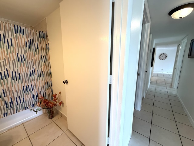 hallway featuring light tile patterned flooring and baseboards