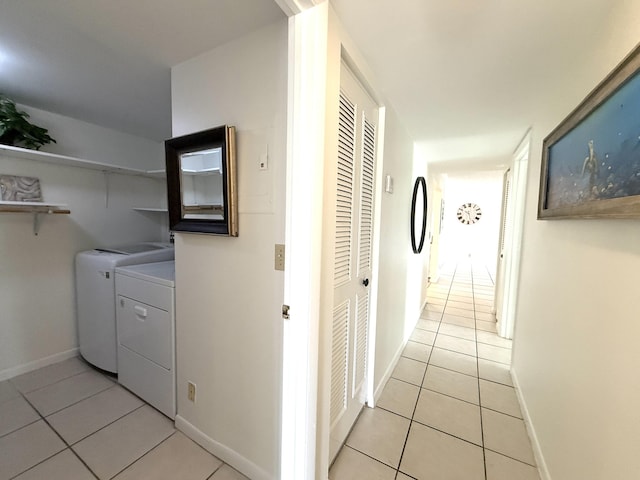 laundry area featuring washing machine and dryer, light tile patterned floors, and baseboards