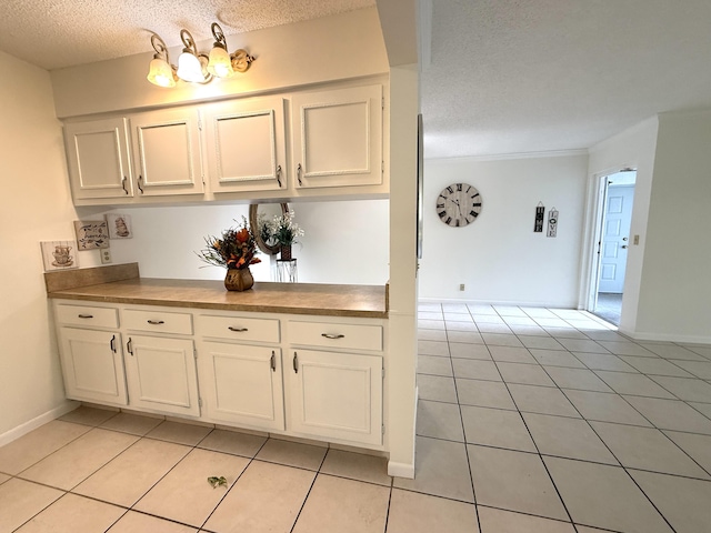 kitchen featuring a textured ceiling, light tile patterned floors, white cabinetry, and baseboards