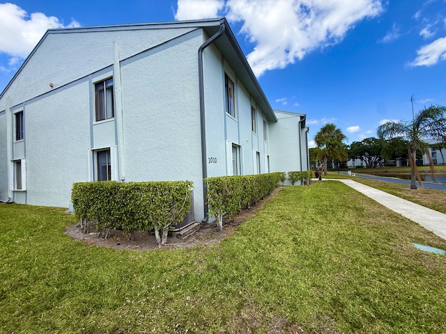 view of side of home featuring stucco siding and a yard