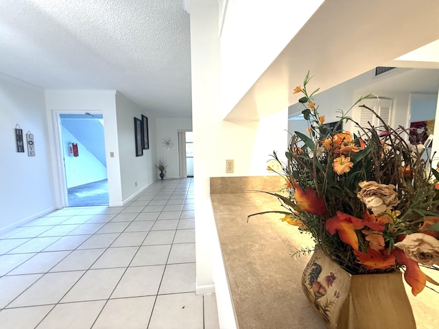 hallway with light tile patterned floors and a textured ceiling