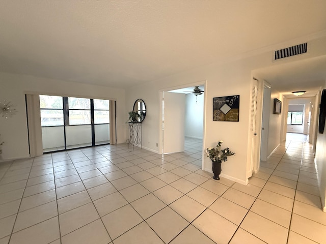 empty room with ceiling fan, light tile patterned floors, healthy amount of natural light, and baseboards