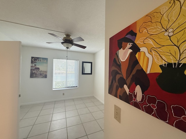 unfurnished room featuring a ceiling fan, baseboards, and a textured ceiling