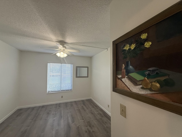 unfurnished room featuring a textured ceiling, wood finished floors, ceiling fan, and baseboards