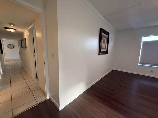 hall featuring wood finished floors, ornamental molding, and baseboards