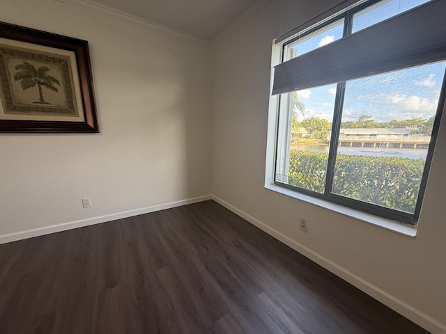 empty room featuring baseboards, plenty of natural light, crown molding, dark wood-style flooring, and a water view