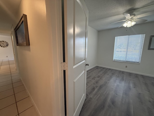 hall featuring baseboards, a textured ceiling, and wood finished floors