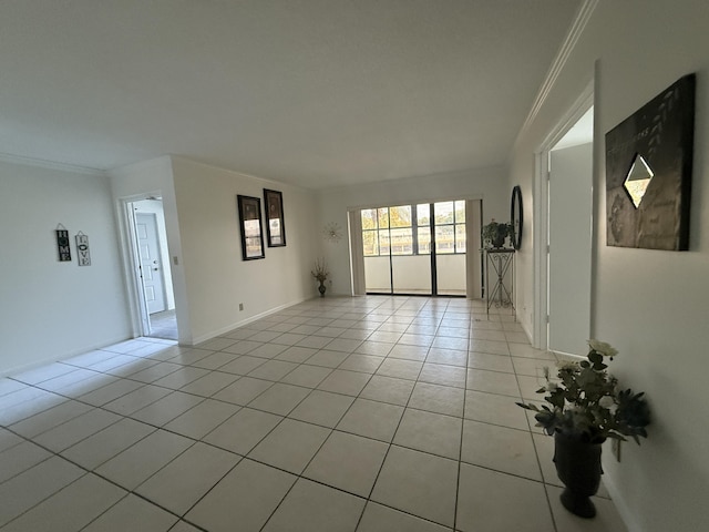 spare room featuring light tile patterned floors, crown molding, and baseboards