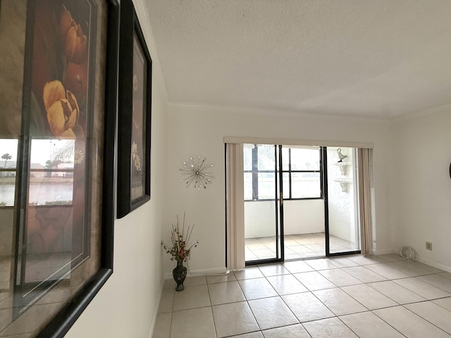 spare room with light tile patterned floors, crown molding, a textured ceiling, baseboards, and a water view