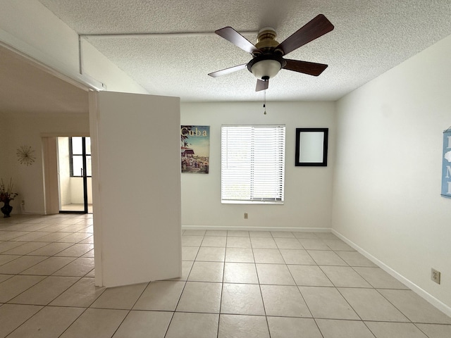 unfurnished room featuring a textured ceiling, a ceiling fan, light tile patterned flooring, and baseboards