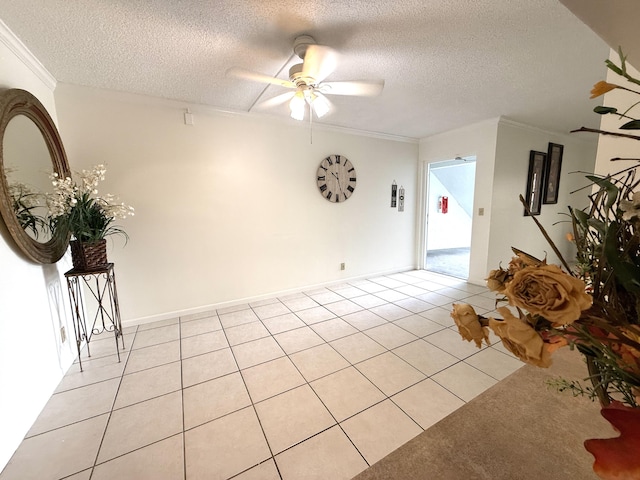 spare room with ceiling fan, a textured ceiling, light tile patterned floors, and crown molding