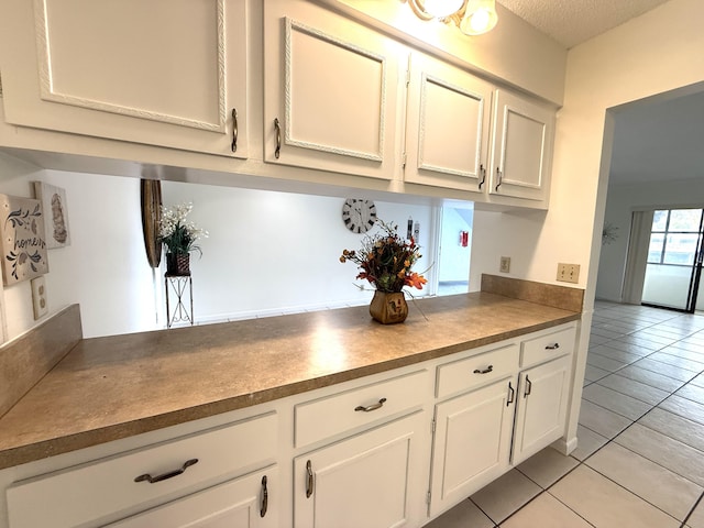 kitchen featuring white cabinetry, light tile patterned floors, and a textured ceiling