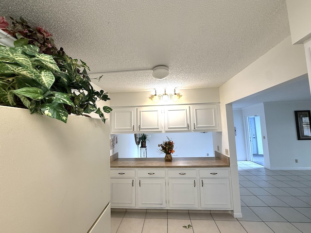 kitchen featuring white cabinets, light tile patterned flooring, and a textured ceiling