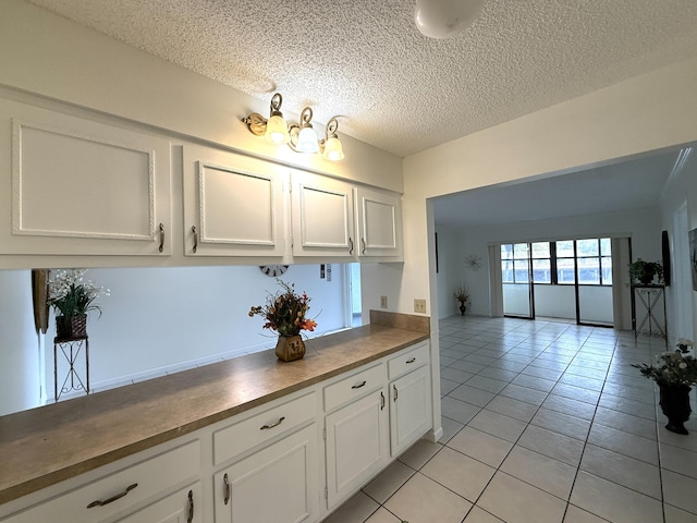 kitchen featuring white cabinets, light tile patterned floors, and a textured ceiling