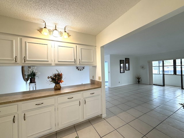 kitchen with light tile patterned flooring, white cabinetry, a textured ceiling, and open floor plan