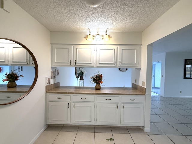 bathroom with tile patterned flooring, a textured ceiling, and baseboards