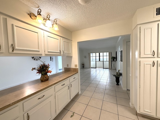 kitchen with white cabinetry, light tile patterned floors, and a textured ceiling