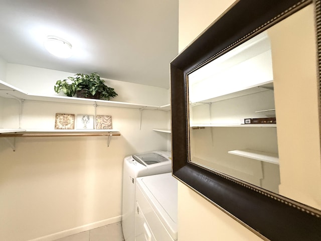 washroom with washing machine and clothes dryer, light tile patterned floors, and baseboards