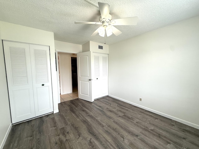 unfurnished bedroom featuring dark wood-type flooring, baseboards, a textured ceiling, ceiling fan, and a closet