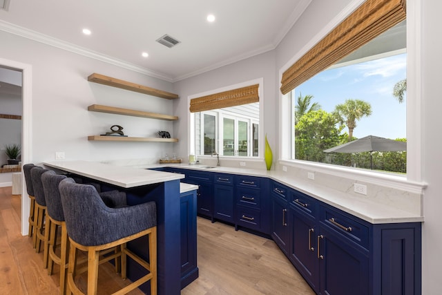 19100 SE County Line Rd, Jupiter, FL 33469 - kitchen with blue cabinetry, a breakfast bar, light wood-style floors, crown molding, and light countertops