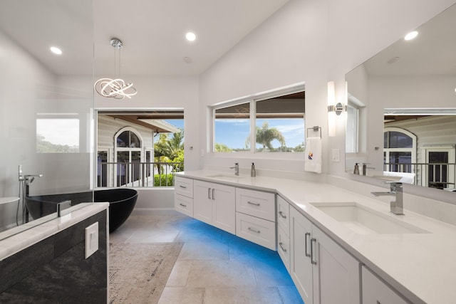 19100 SE County Line Rd, Jupiter, FL 33469 - bathroom featuring double vanity, a freestanding tub, recessed lighting, a chandelier, and tile patterned flooring