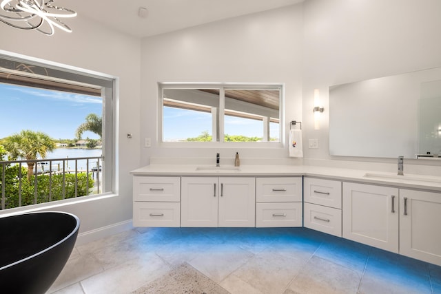 19100 SE County Line Rd, Jupiter, FL 33469 - bathroom featuring double vanity, baseboards, a soaking tub, a water view, and tile patterned floors
