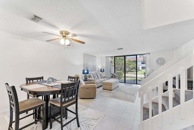 dining room featuring visible vents, a textured ceiling, ceiling fan, and stairway