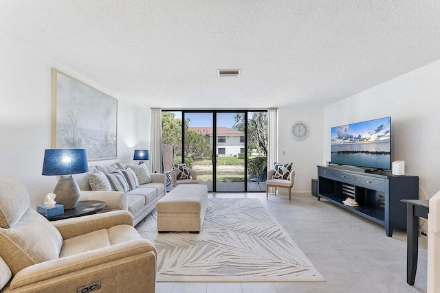 living area with visible vents, a textured ceiling, light tile patterned flooring, and a wall of windows