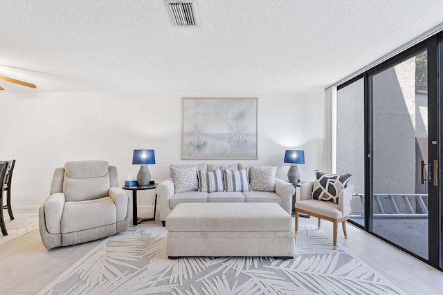 living room with a textured ceiling, ceiling fan, and visible vents