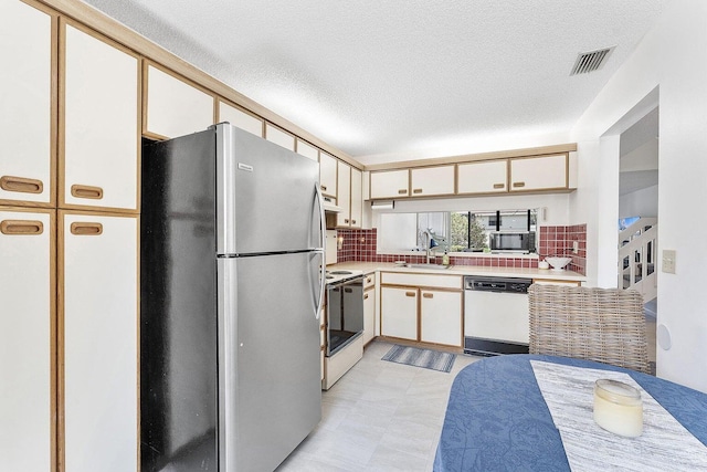 kitchen with visible vents, light countertops, tasteful backsplash, a sink, and stainless steel appliances