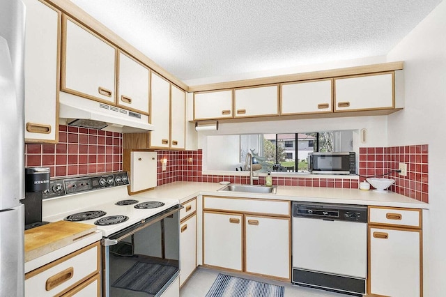 kitchen with a textured ceiling, appliances with stainless steel finishes, a sink, light countertops, and under cabinet range hood
