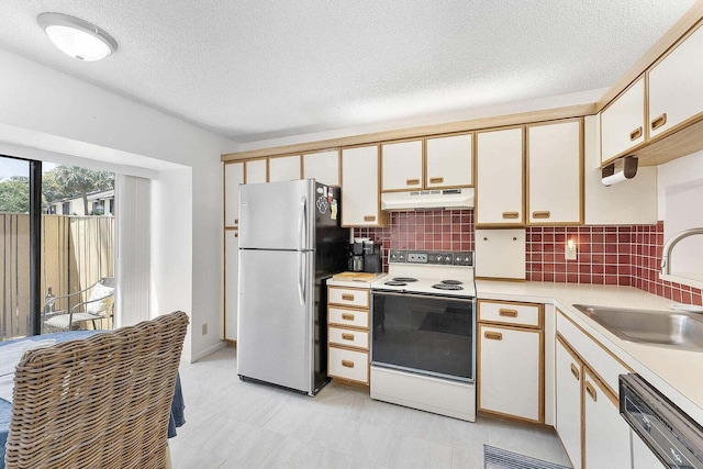 kitchen featuring white appliances, light countertops, under cabinet range hood, tasteful backsplash, and a sink